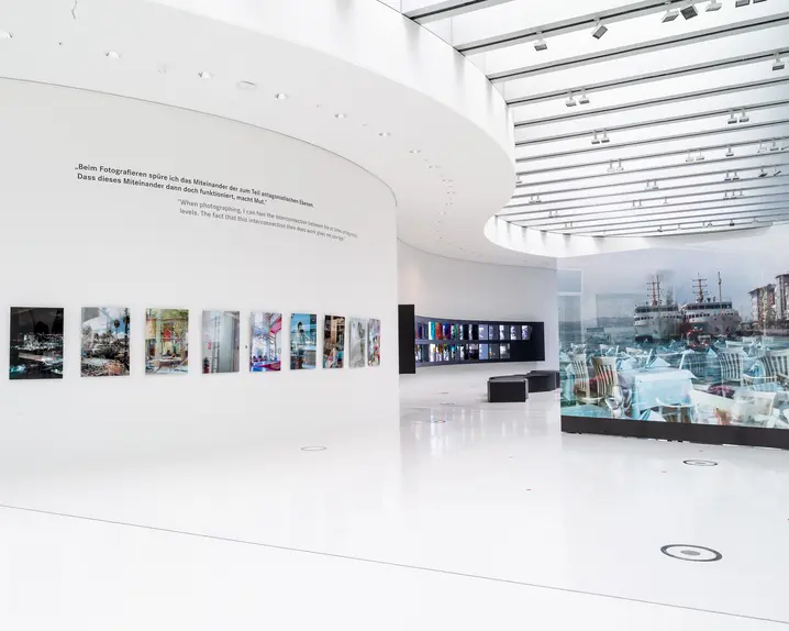 Bright, modern exhibition space with photographs on a white, curved wall.