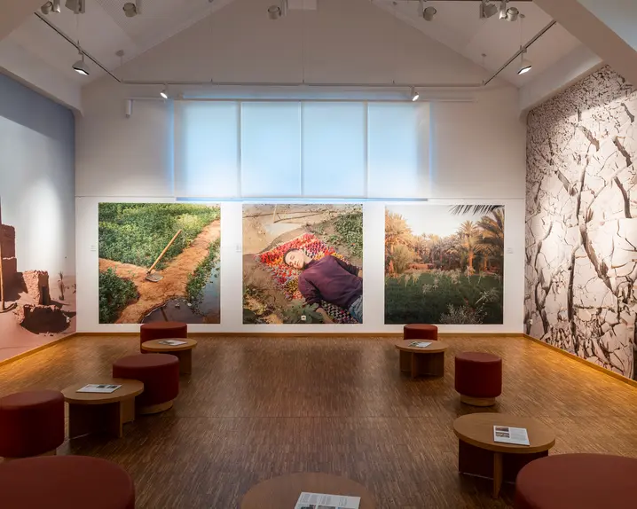 Gallery in a modern, bright design with large landscape photographs and round stools.