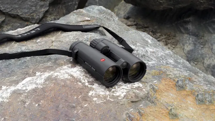 The Leica Noctivid lies on rocky ground