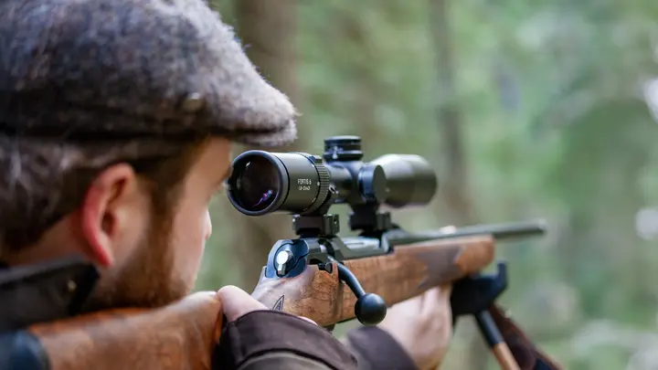 The focus is on the Leica Fortis while a hunter gazes intently through the scope
