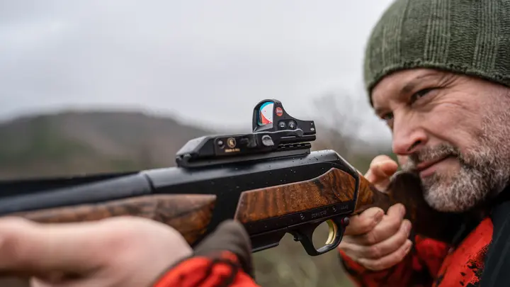 The focus in this image is on the Leica Tempus, where a man is looking intently through the red dot sight