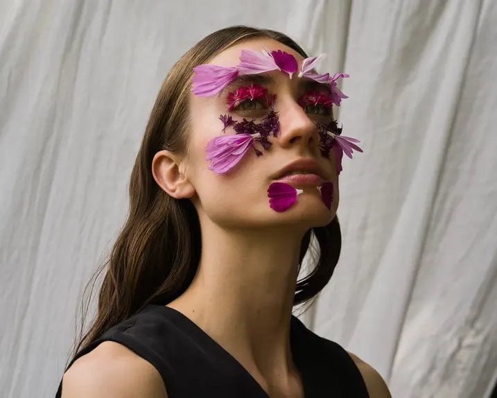 Ein Portrait einer Frau mit Blumen auf ihrem Gesicht.