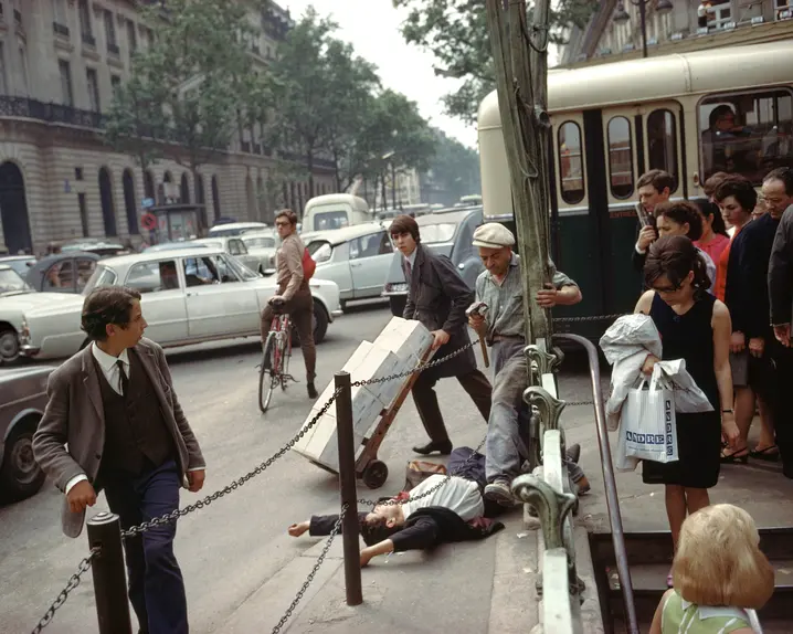 A young man in a suit and tie lies on his back with arms stretched above his head, directly next to the metro station