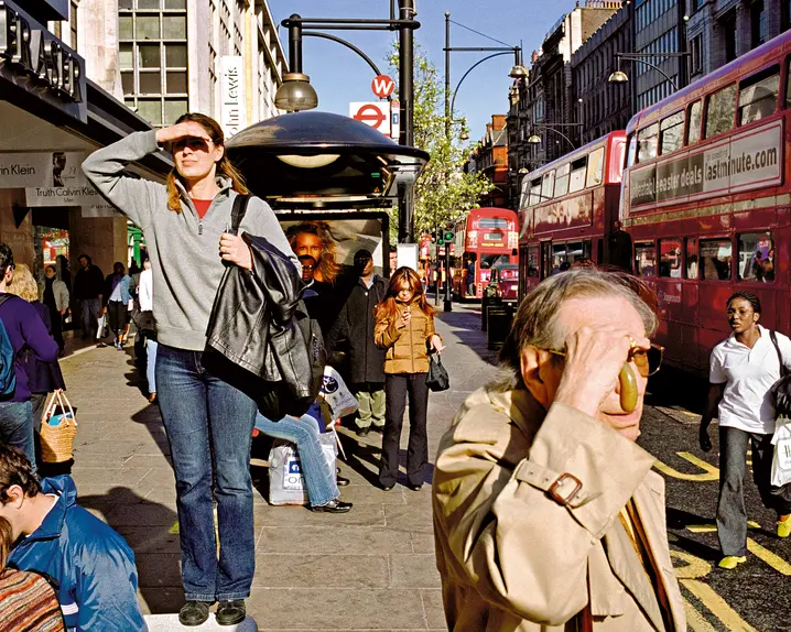 A woman who was standing on a bench, appearing to be looking for something and other people