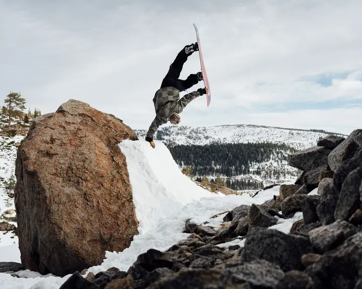 Snowboarder does a one-armed handstand on a ramp in the mountains