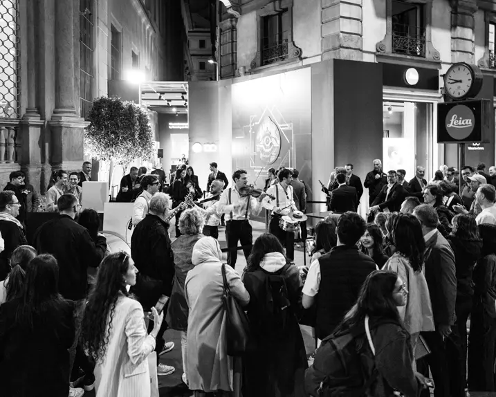 Guests at the celebrations stand in front of the Leica Store in Milan watching street musicians.