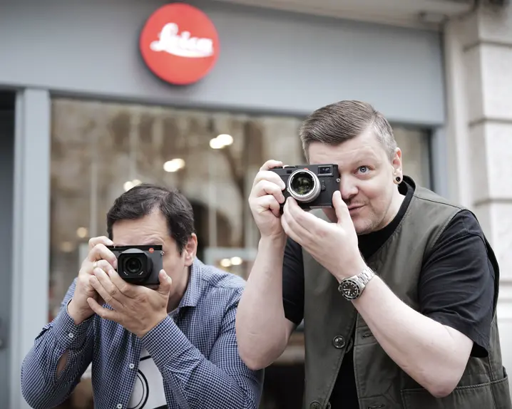 Two sales associates standing infront the Leica Store Berlin and taking pictures with Leica Cameras