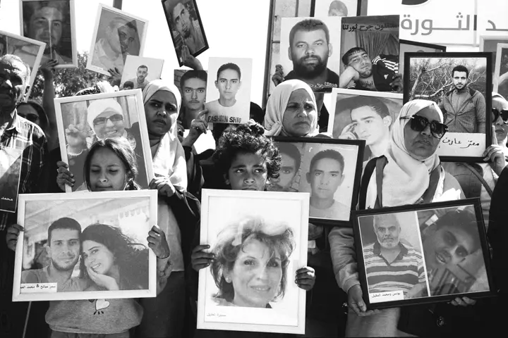 Some people hold up pictures of missing or deceased persons from the Syrian war in picture frames