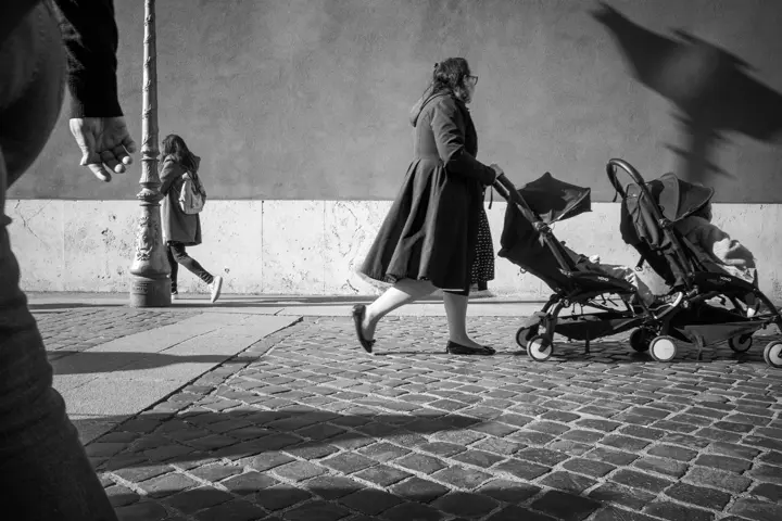 Woman pushing a pram through the streets, black and white photograph