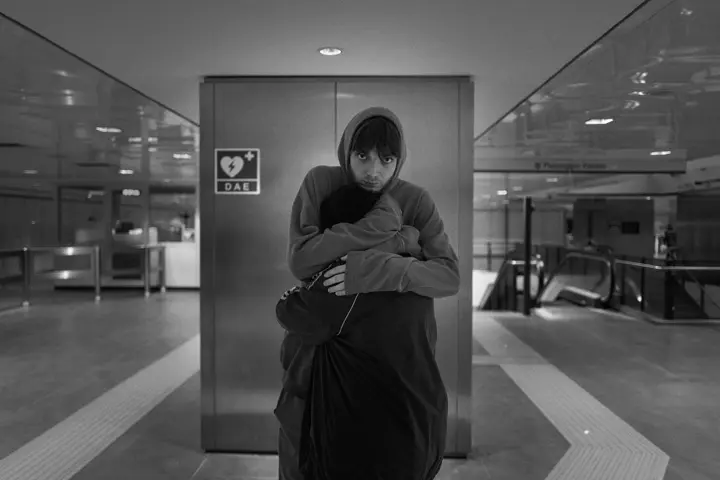Black and white street photograph of a boy comforting a younger boy with a hug at the train station