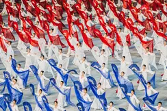 North Korean women dance with hand fans and transparent cloths in white, red and blue. 