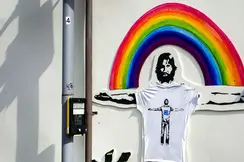 A mural on the wall of a man with outstretched arms in front of a rainbow.