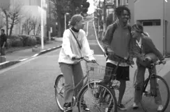 Three young people stand on bicycles in the street and laugh together.