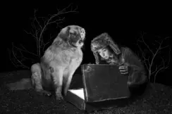 Viktoria Sorochinski and a dog looking into an old suitcase that is glowing inside. 