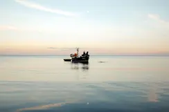 A person in a small boat fishing in the sea.