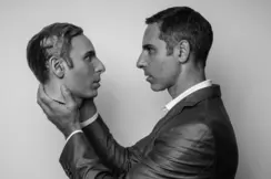 A man holds an artificial head in his hands and looks directly into its eyes.