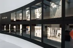 An exhibition of black and white photographs of famous events, presented in two curved rows.