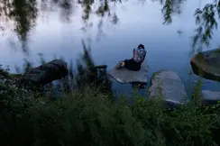 Woman sitting on a stone by the lake