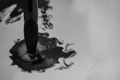 Brush dips into dark ink that spreads in the water.