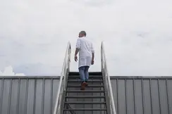 A man walks up a staircase with a cloudy sky in the background.