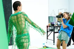 Photographer takes a picture in a studio of a model in a green net outfit.