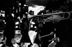 Several musicians and a trumpeter in the foreground play music in the street