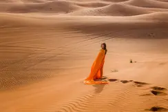 Woman in an orange dress standing in the desert.