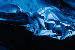 A glowing blue ice formation in a dark cave.