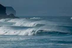 Waves breaking on a coastline under a blue sky