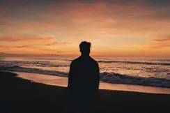 Silhouette of a man watching the sunset on the beach.
