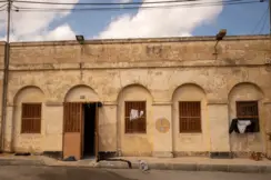 Older stone building with barred windows and clothes hanging outside.