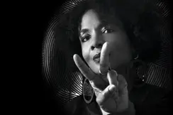 Black and white portrait of a woman with an Afro hairstyle making the peace sign