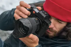 Close-up of a photographer with a red cap looking through the camera