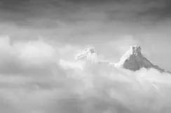 Two snow-covered mountain peaks protrude through a blanket of cloud.