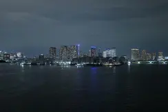 Illuminated skyline of Tokyo at night, with a view of the water in the foreground.
