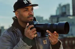 A young man is taking pictures with a cityscape in the background