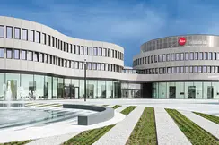 Modern architecture with Leica logo and curved glass facades and a fountain in front of the building.