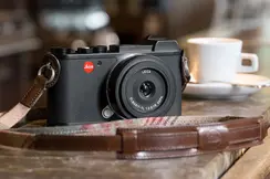 Leica camera on wooden counter with coffee cup in background