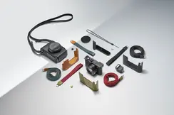 Camera with various accessories, such as straps and protective covers, on a light background