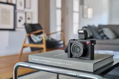 Leica D-Lux 8 placed on a book lying on a table.