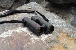 The Leica Noctivid lies on rocky ground