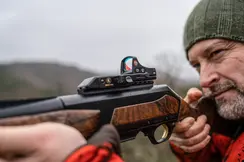 The focus in this image is on the Leica Tempus, where a man is looking intently through the red dot sight