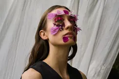 Ein Portrait einer Frau mit Blumen auf ihrem Gesicht.