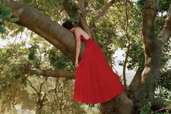Woman with a red dress hangs in a tree
