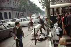 A young man in a suit and tie lies on his back with arms stretched above his head, directly next to the metro station