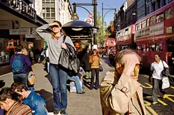 A woman who was standing on a bench, appearing to be looking for something and other people