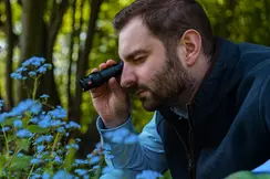 a man looking at a flower through the monovid from nearby