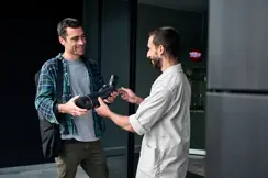 A man hands a Leica APO-Televid spotting scope to a customer