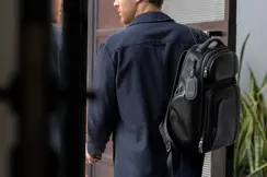 Man wearing a suit with a rucksack and a Leica leather tag