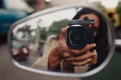 Woman taking a picture with the Leica Q into a side mirror